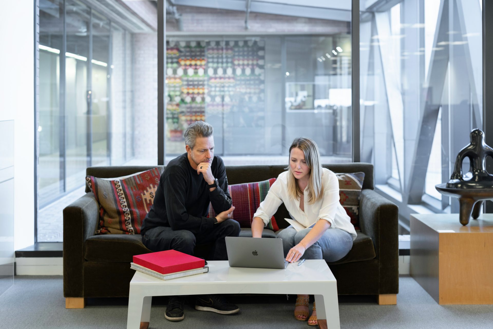 Mann und Frau sitzen auf der Couch und benutzen ein MacBook